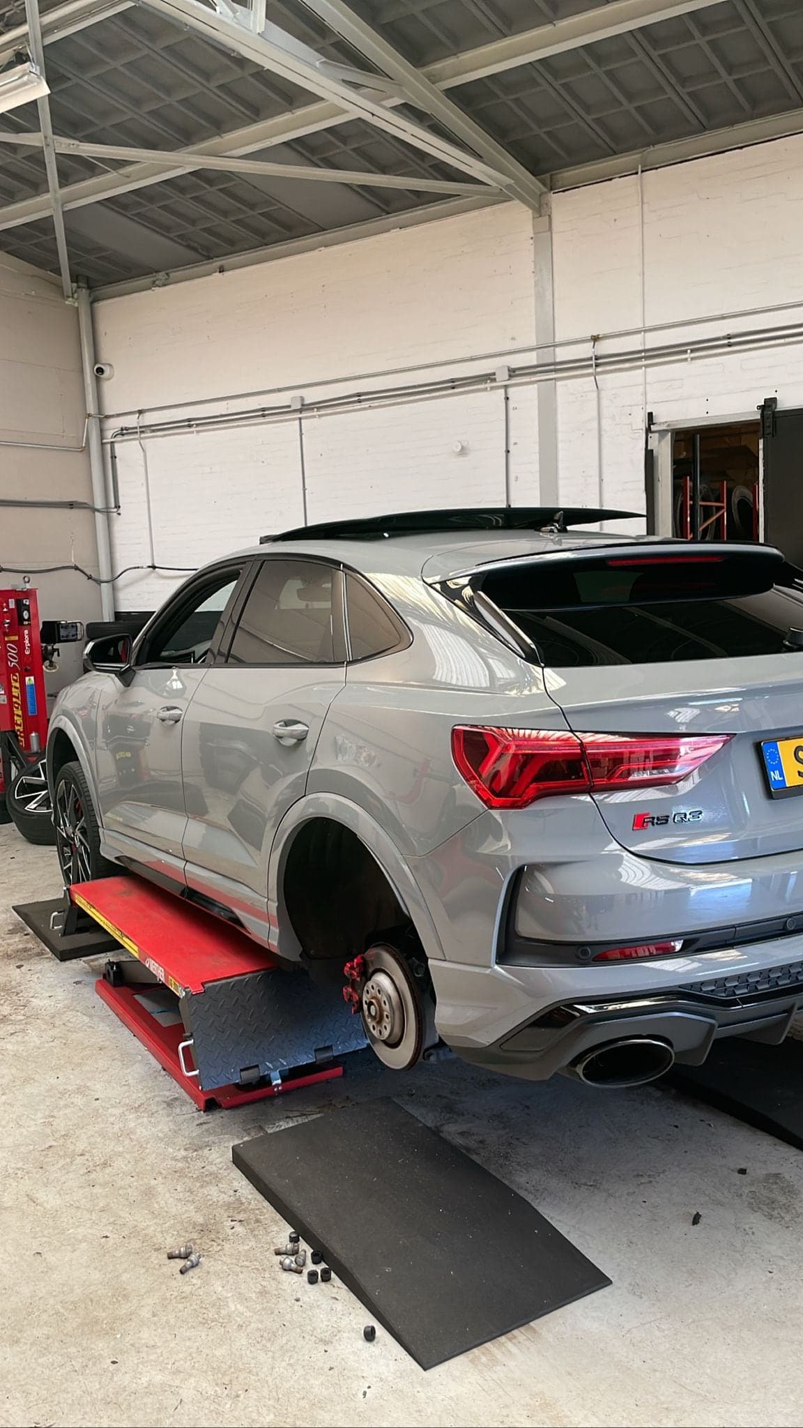 Een grijze Audi Q3 op de hefbrug in de werkplaats