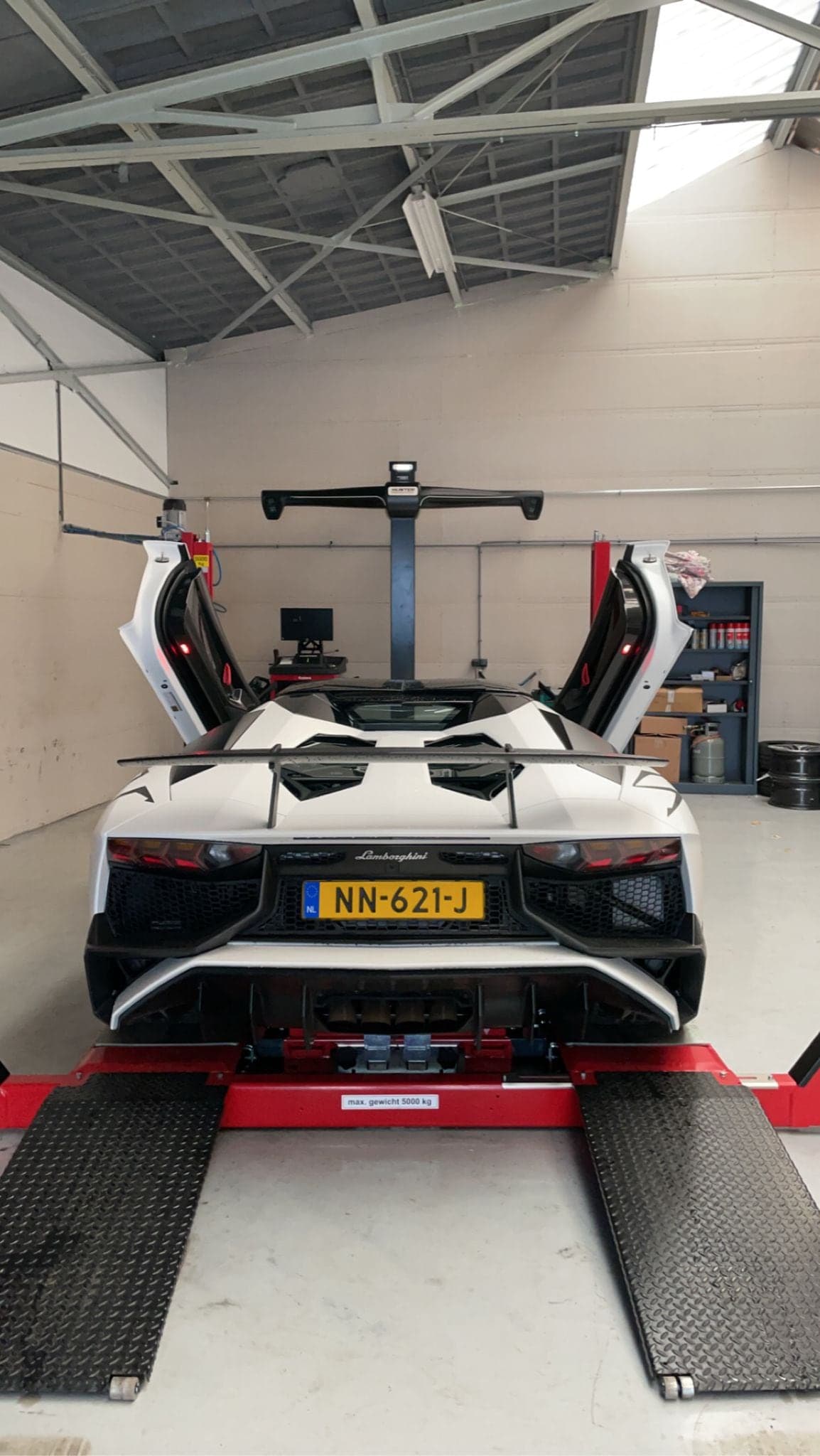 Een witte Lamborghini Aventador met geopende deuren op de Hunter 3D uitlijnbrug