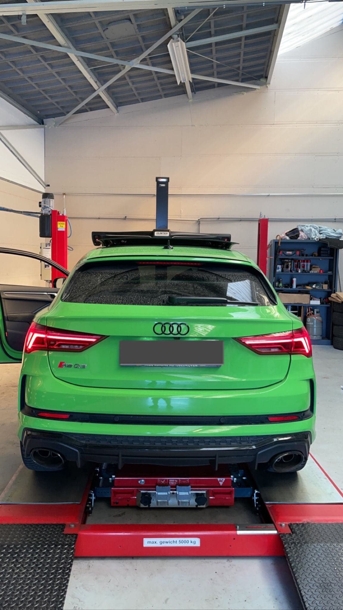 Een groene Audi RS3 op de uitlijnbrug tussen de hefarmen