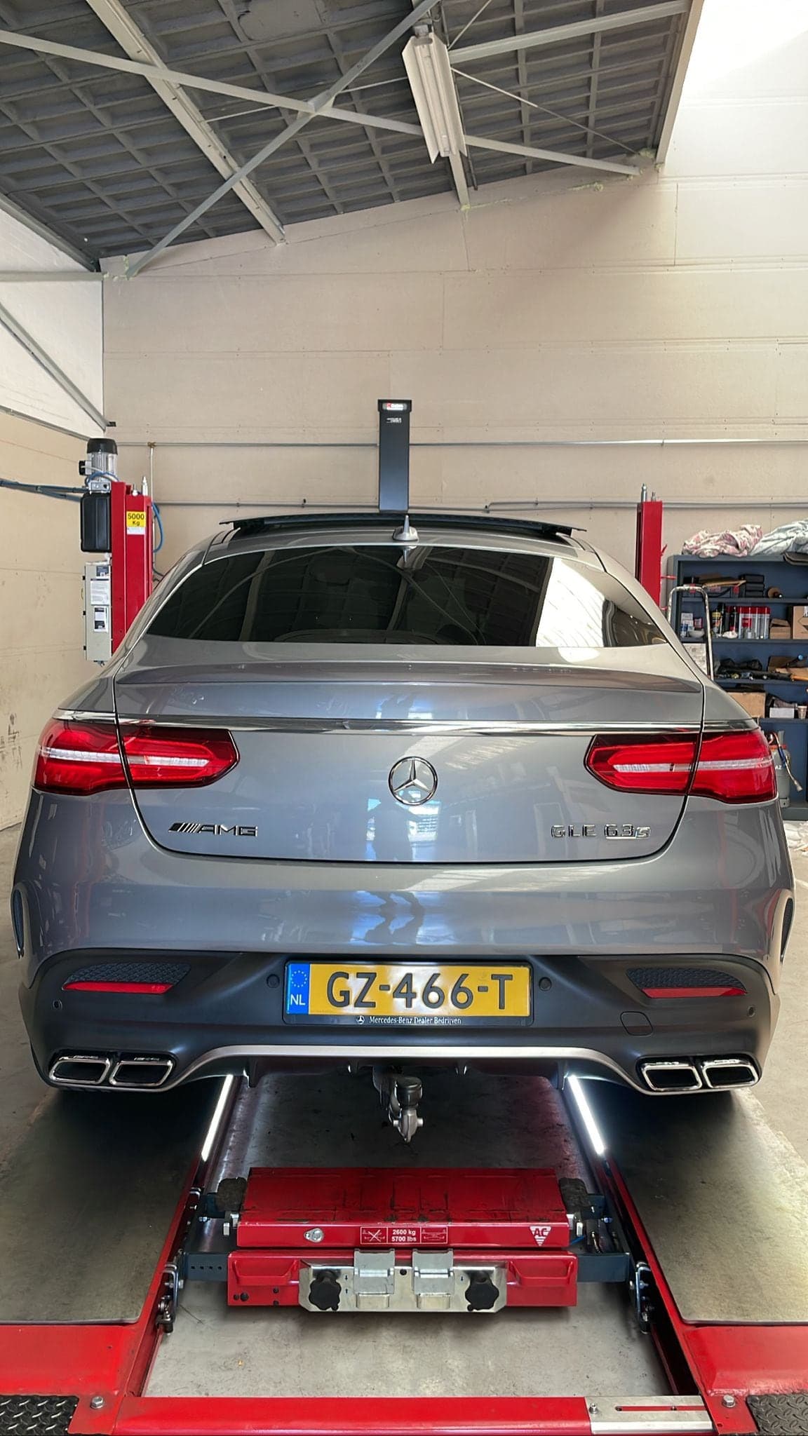 Een grijze Mercedes AMG GLE Coupé op de uitlijnbrug in de werkplaats