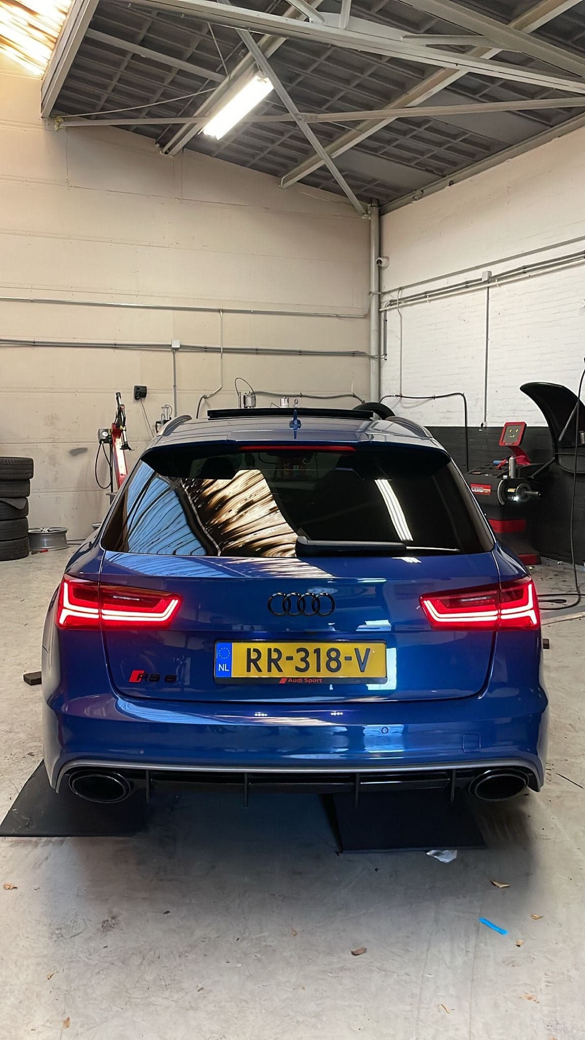 Een blauwe Audi RS met geopende achterklep op de 3D uitlijnbrug