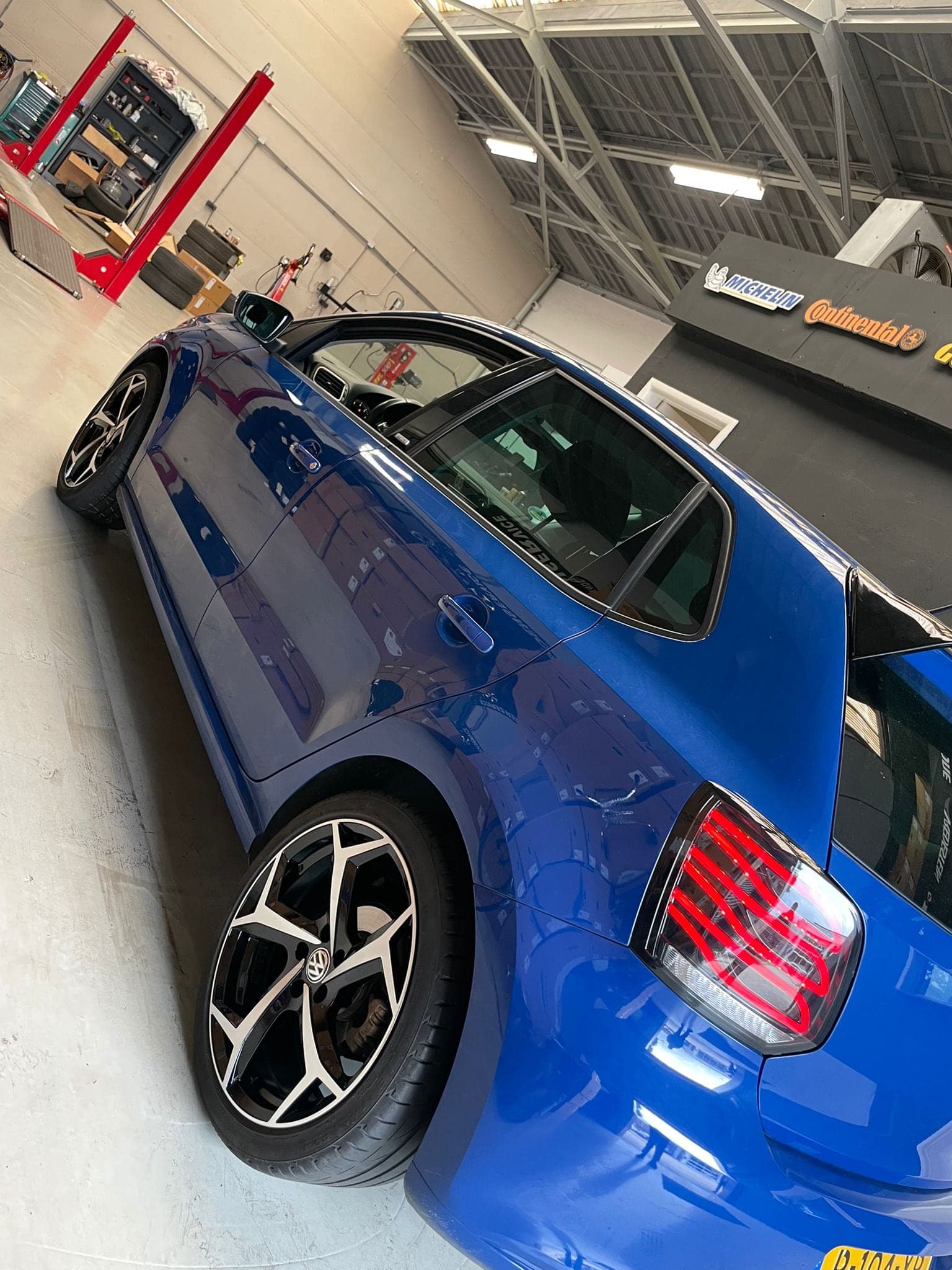 Zijaanzicht van een blauwe Audi met zwarte lichtmetalen velgen in de werkplaats