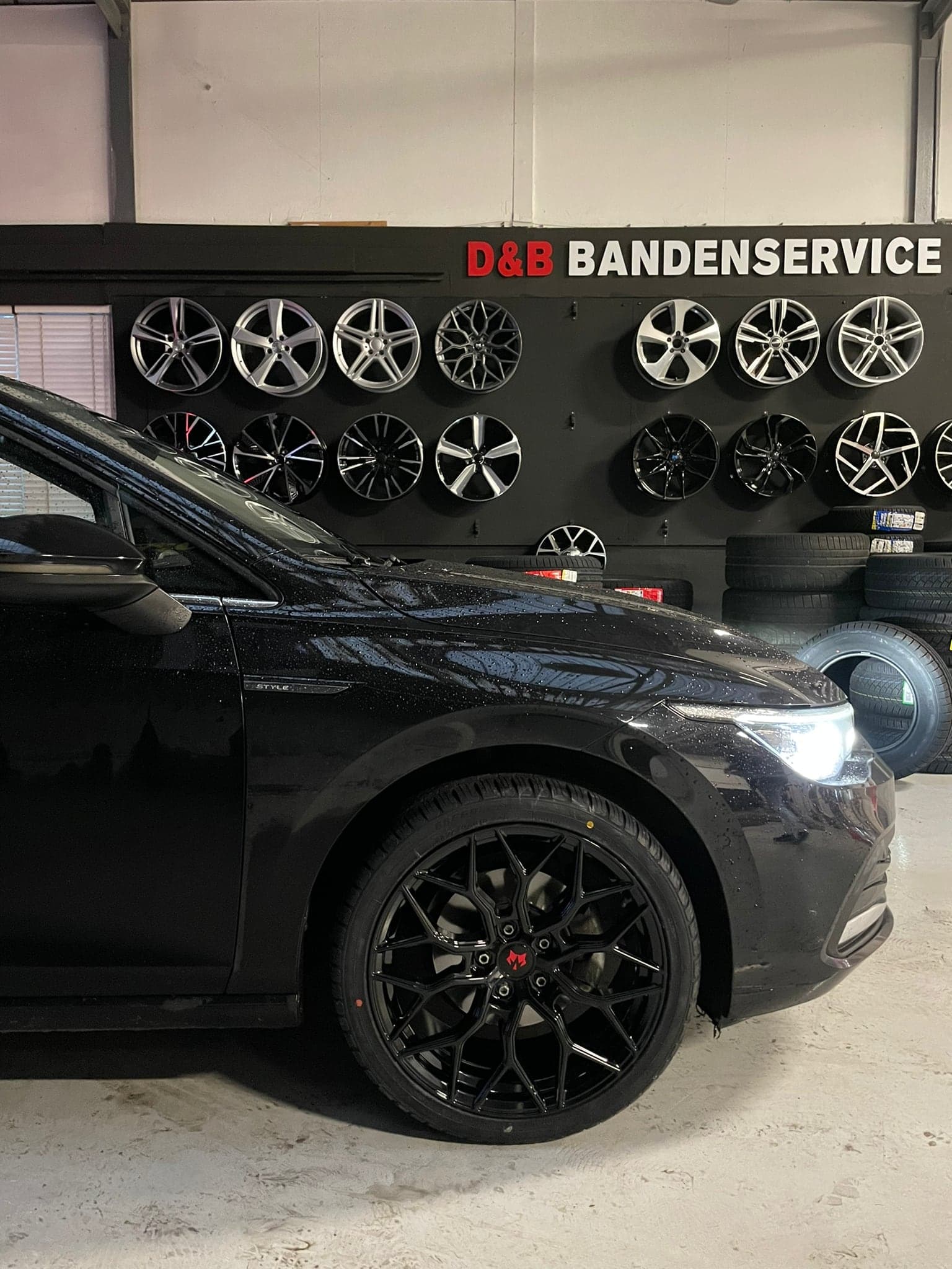 Donkere auto voor de wand met lichtmetalen velgen in de showroom