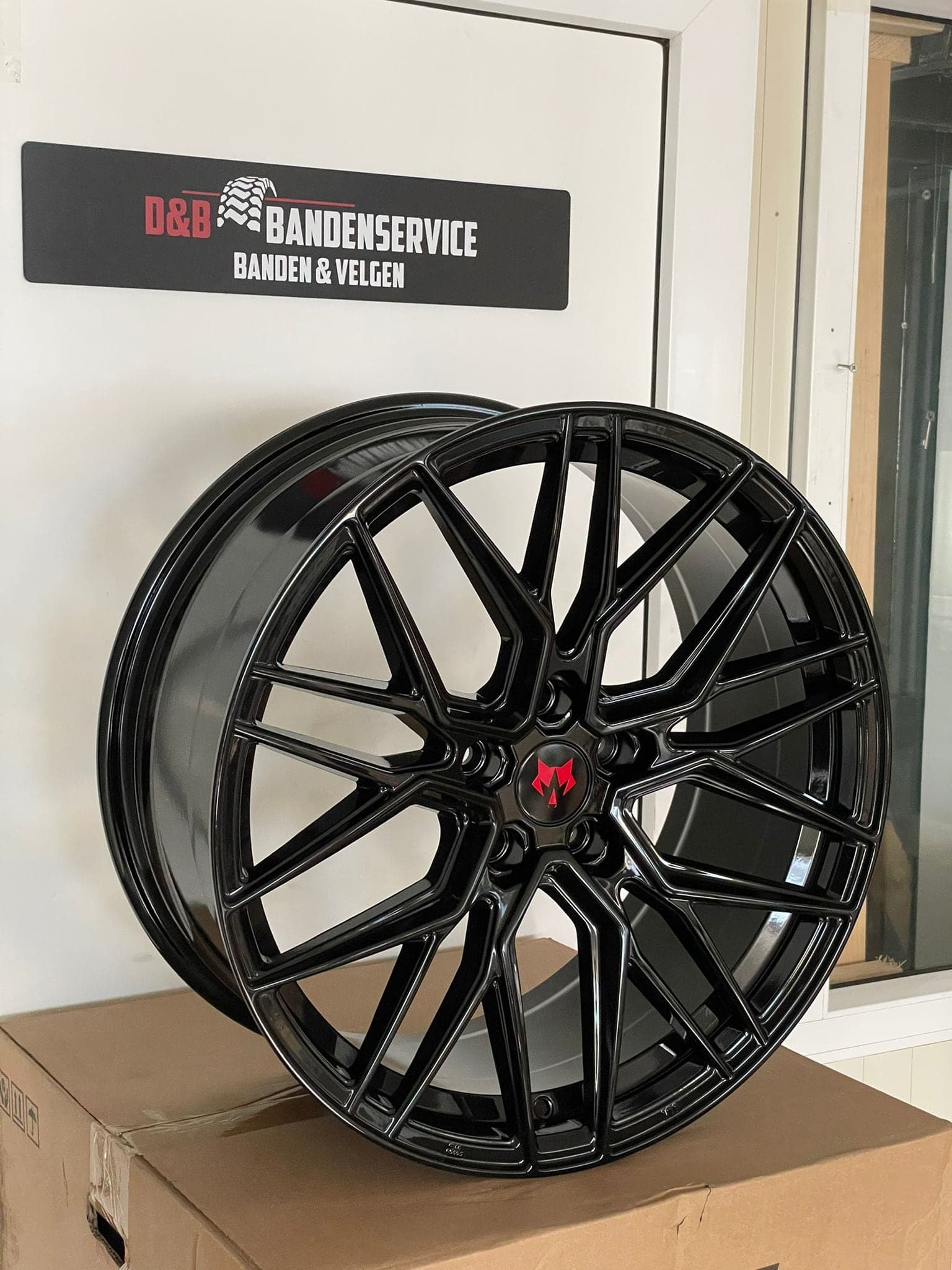 Zwarte lichtmetalen velg met rode remklauw, gemonteerd door D&B Bandenservice