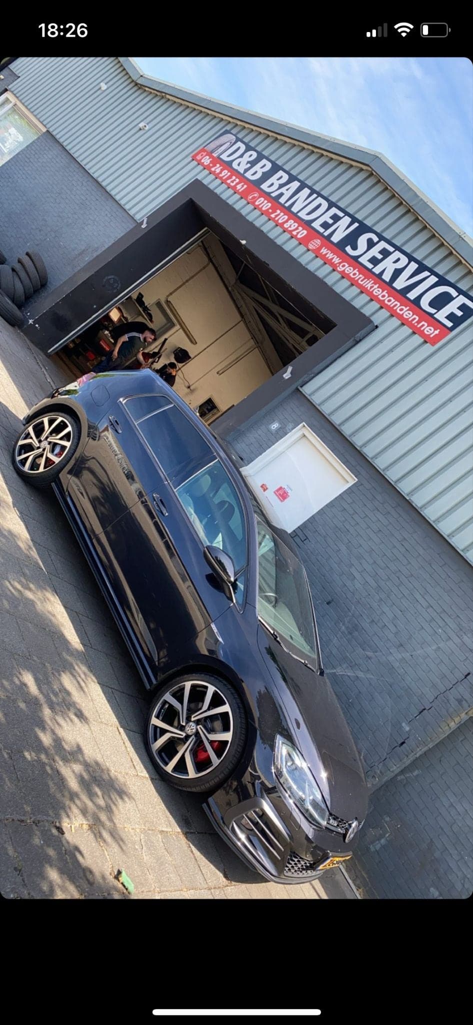 Klantauto naast de blauwe werkplaatsdeur van D&B Bandenservice